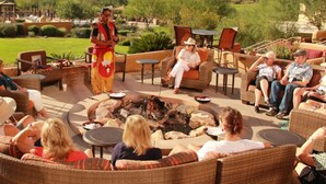 An outdoor seating area with wicker furniture, a fire pit, and a view of a mountainous landscape.