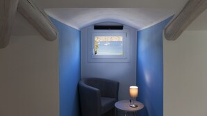A small room with a blue wall, a window with a view of boats, a chair, and a table with a lamp. - GIGLIO E MAREA - MAREA (Campo nell'Elba)