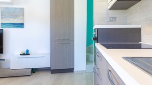 A modern kitchen with a built-in oven, a microwave, and a sink. There is a small seating area with a table and a chair. - GIGLIO E MAREA - MAREA (Campo nell'Elba)