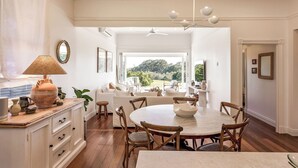 A spacious dining area with a round table and wooden chairs, a white sofa set, and a view of the outdoors. - Buttercup Farm Yallingup (Yallingup)