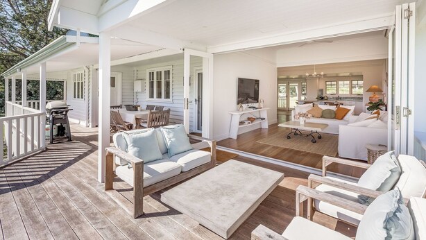 A spacious outdoor deck with a white railing, a grill, and a seating area with a sofa and chairs. - Buttercup Farm Yallingup (Yallingup)