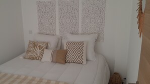 A bed with patterned pillows and a plain headboard.