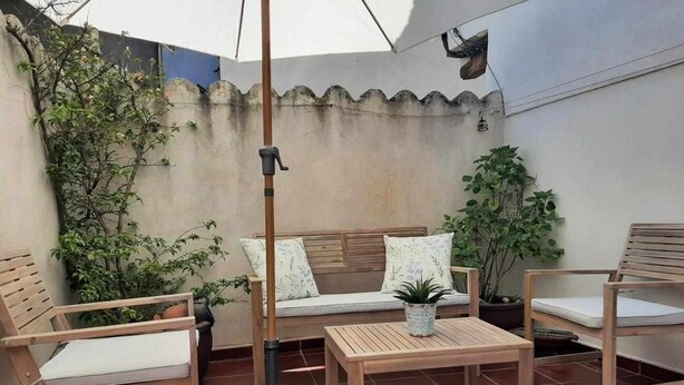 A patio with wooden furniture, including a sofa, two chairs, and a table.