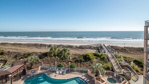Zona de piscina con vista a la playa y al océano.