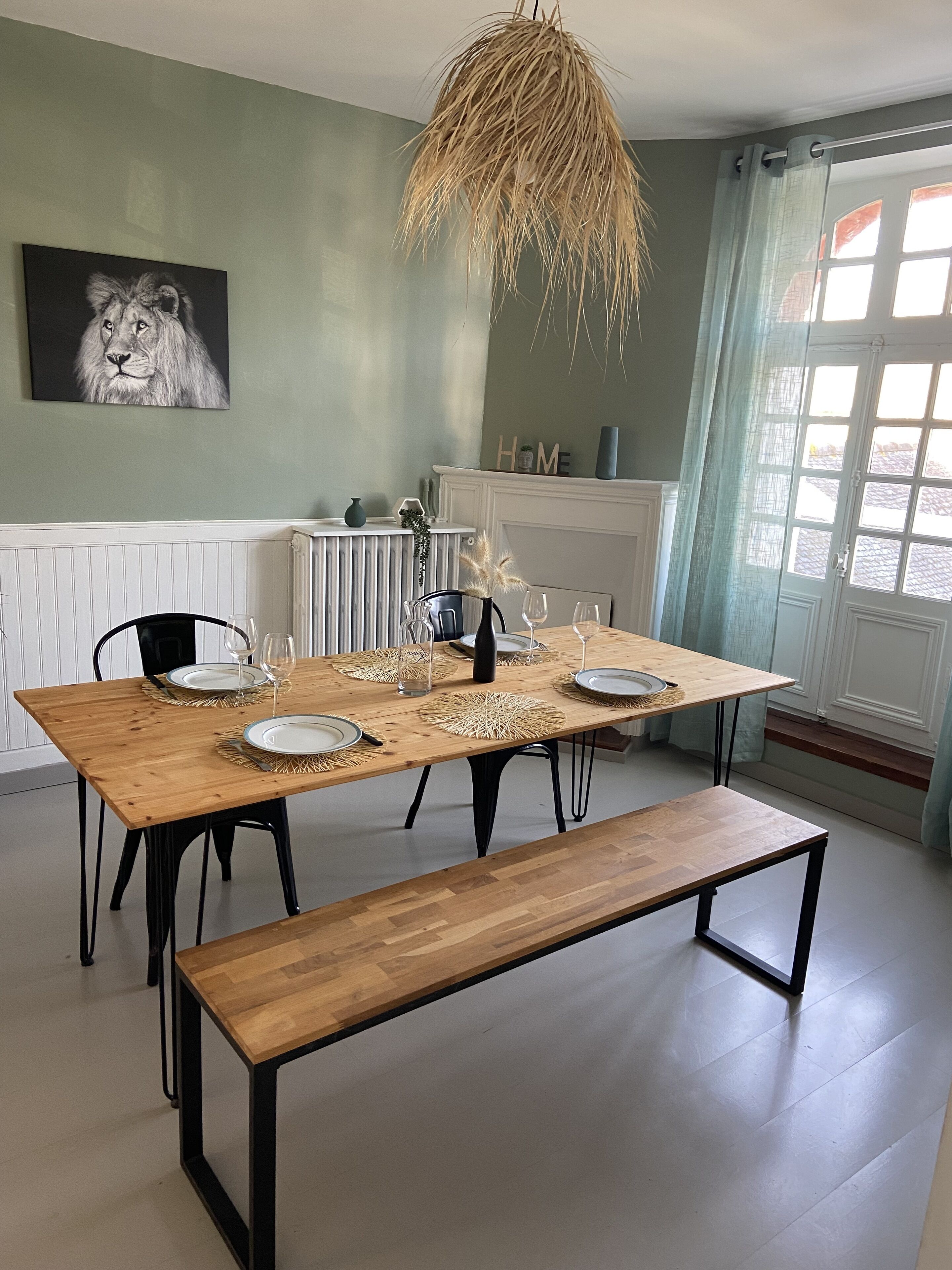 A dining area with a wooden table set for four, a bench, and a painting of a lion on the wall.