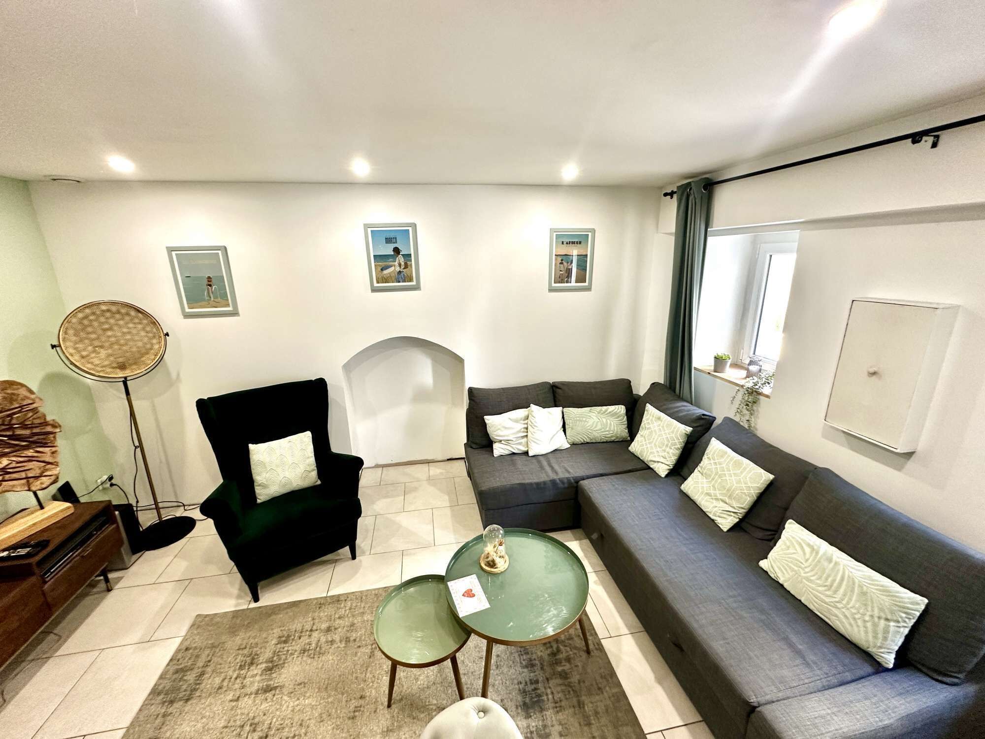 A modern living room with a sectional sofa, a black armchair, a round floor lamp, and a small glass table.