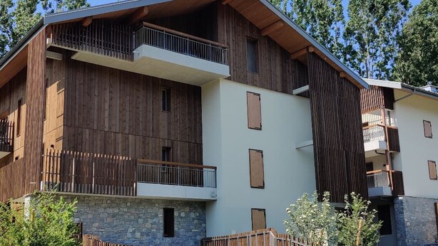 A multi-story building with a combination of wooden and stone facades, balconies, and a stone base.