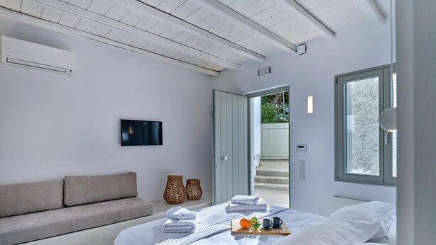 Un dormitorio moderno con cama, sofá, televisión y ventana.