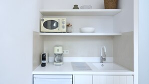 Una kitchenette compacta con microondas, cafetera y lavabo.