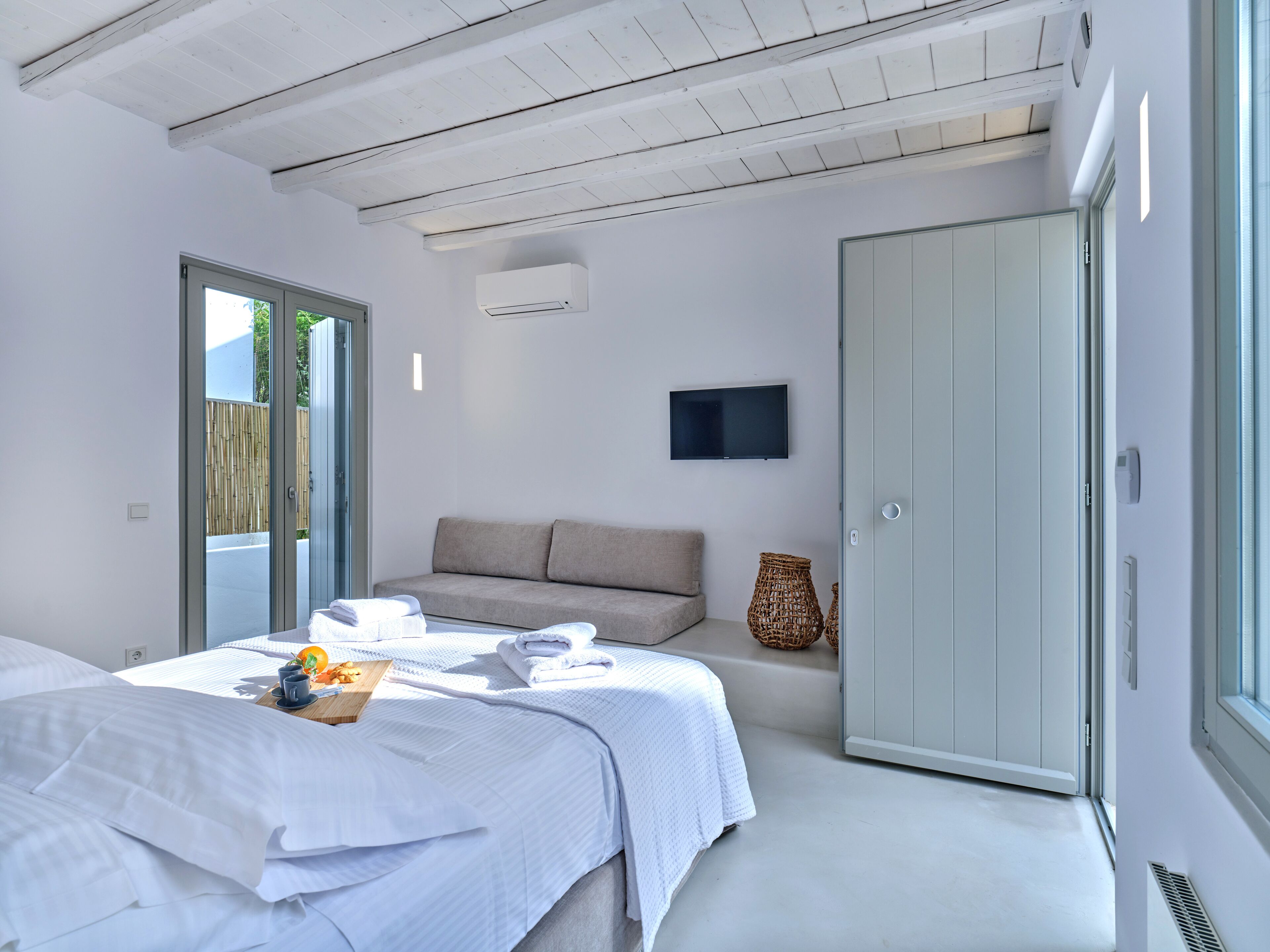 A modern bedroom with a bed, a sofa, a TV, and a wardrobe.