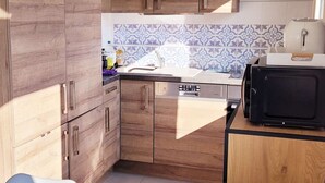 A compact kitchen with wooden cabinets, a dishwasher, and a microwave.