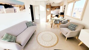 A modern living room with two sofas, a dining table, and a kitchen in the background.