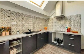 Kitchen features a geometric patterned backsplash, dark cabinetry, and a stainless steel sink.
