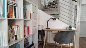 A study area with a desk, chair, bookshelf, and a staircase.
