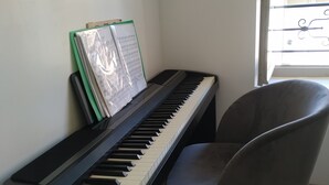 A piano with sheet music, a chair, and a window with a view of the outside.