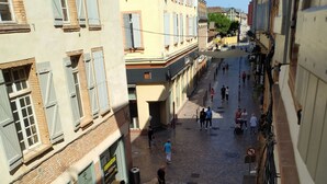 A cobblestone street with buildings on either side, a bicycle, and people walking.