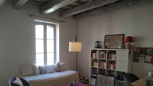 A cozy room with a bed, a desk, a bookshelf, and a window.