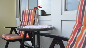 A small outdoor seating area with striped chairs and a round table, featuring a vase with flowers. - Fewo Haus ,,eckernf örde (Schönberg)