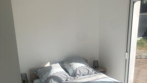 Ein Schlafzimmer mit einem Bett, einem Sessel, einem Nachttisch und einem Fenster.