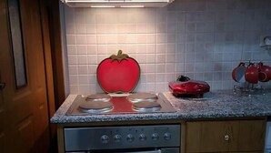 A kitchen with wooden cabinets, a stainless steel stove, and a red apple-shaped light fixture. - Apartment - Sleeps 5 - Parking - Private Terrace (Kalymnos)