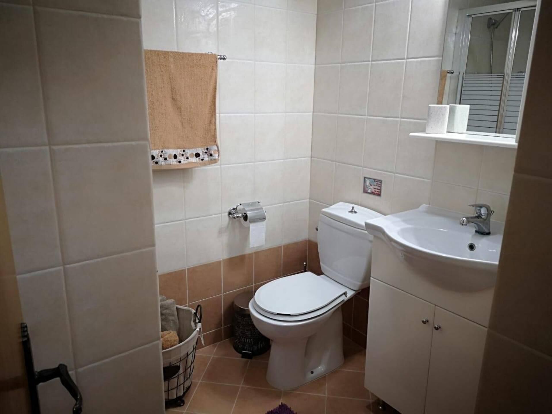 Un baño pequeño con inodoro, lavamanos y un estante sobre el lavabo.