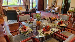 A dining area with a glass table set for six, surrounded by wicker chairs. - Lava House (Pahoa)
