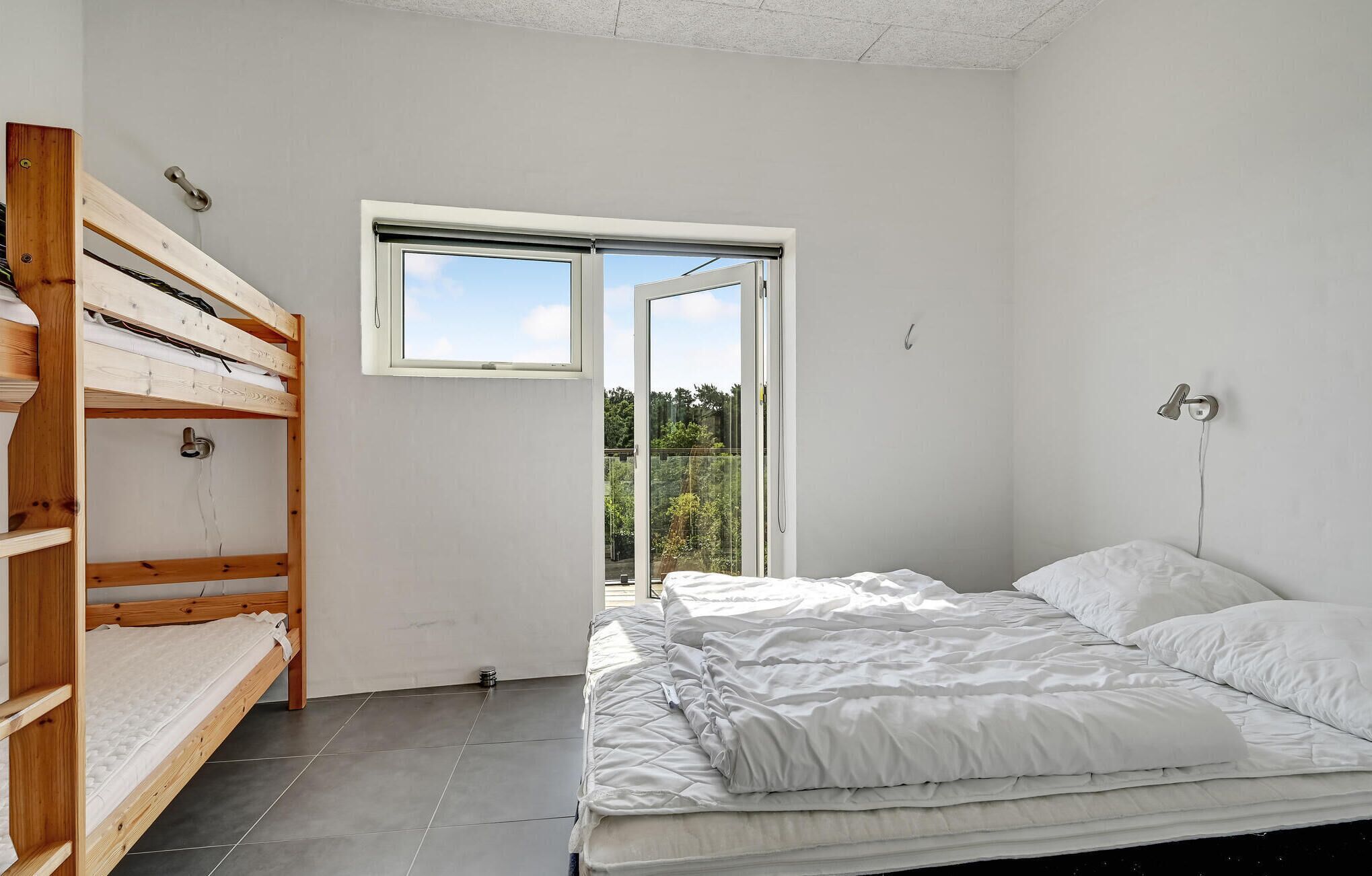 Una camera da letto con un letto a castello, un letto singolo, una finestra vista sul verde e una porta.