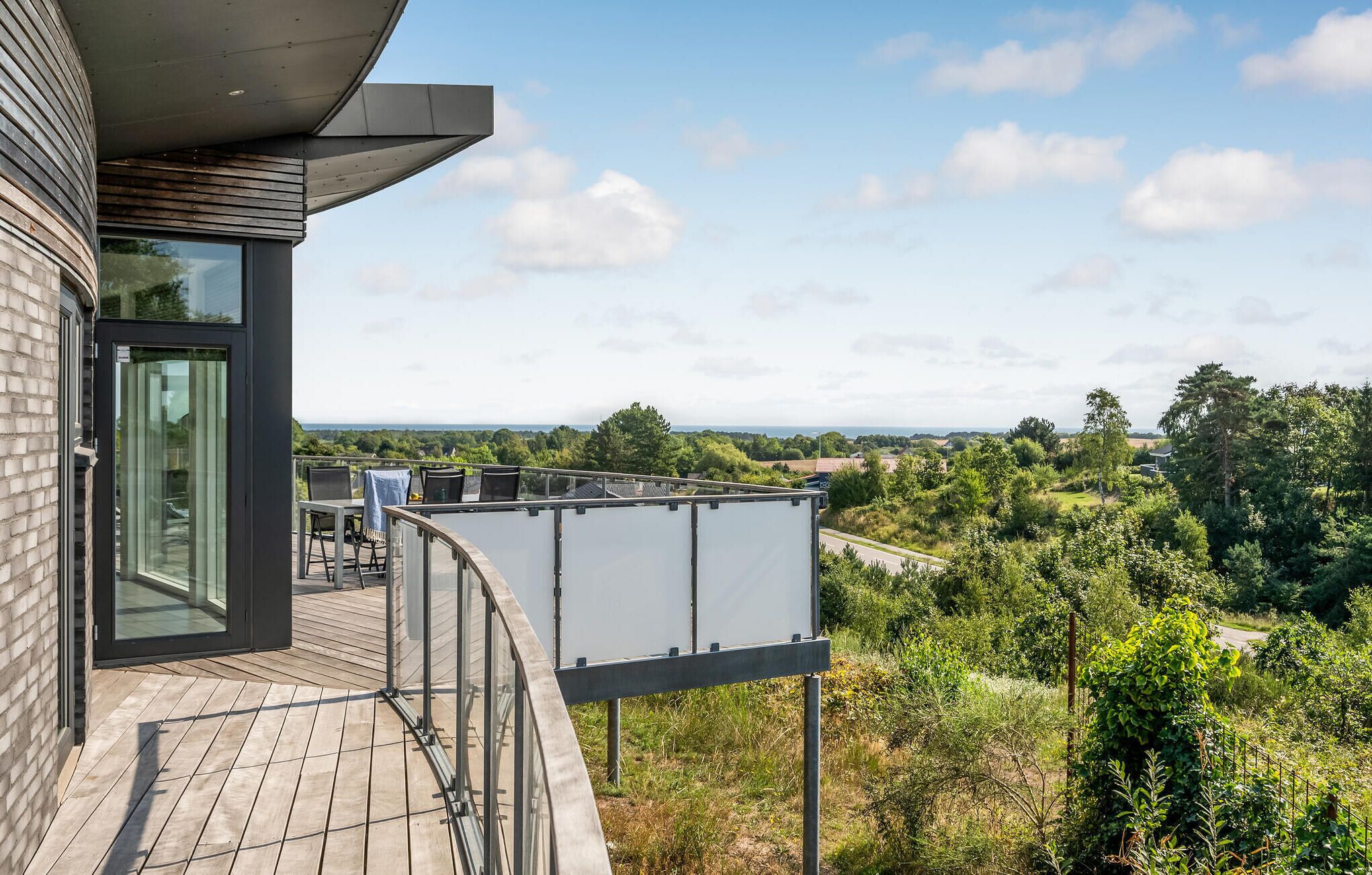 A modern building with a balcony overlooking a lush landscape.