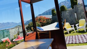 Une terrasse fermée par des baies vitrées, avec une table et des chaises, d’où l’on peut admirer un paysage montagneux.