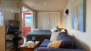 Une chambre d’hôtel avec un lit, un canapé, une télévision et un tableau au mur.