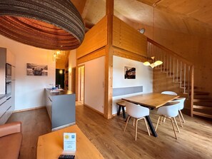 A modern interior with a wooden dining area, a reception desk, and a staircase.