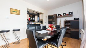 Een moderne keuken met een eethoek, bestaande uit een zwarte tafel en stoelen, een klein barretje en een decoratieve kerstboom.