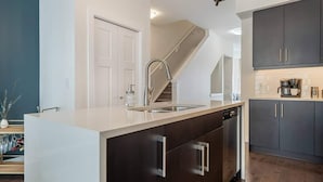 A modern kitchen with a central island, stainless steel appliances, and dark cabinetry.