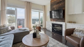 A modern living room with a fireplace, large windows, and a flat-screen TV.