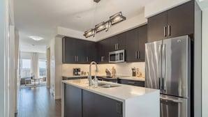 A modern kitchen with dark cabinets, stainless steel appliances, and a large island.