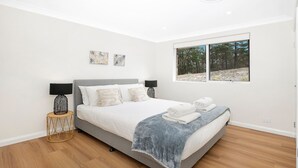 A bedroom with a bed, two bedside lamps, a window with a view of trees, and two wall-mounted artworks. - The Hideaway at Sutton Forest Retreat (Sutton Forest)