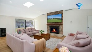 A living room with a fireplace, sofas, a coffee table, and a TV. - The Hideaway at Sutton Forest Retreat (Sutton Forest)