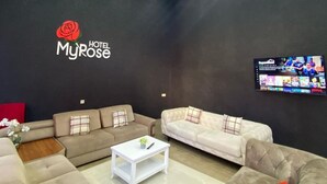 A modern hotel lobby with two sofas, a coffee table, and a TV on the wall. - Hotel MyRose (Batumi)
