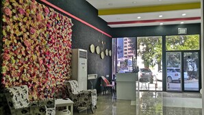 A reception area with a wall of colorful flowers, a clock, and a reception desk. - Hotel MyRose (Batumi)