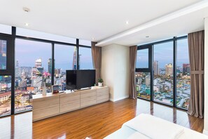 Una habitación de hotel moderna con una amplia vista de la ciudad, un televisor de pantalla plana y piso de madera.