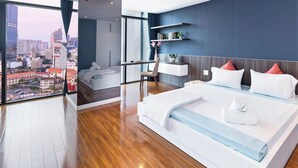 A modern hotel room with a large bed, a desk, and a view of the city.