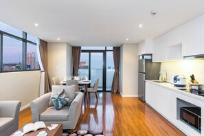 Una habitación de hotel moderna con comedor, sofá, mesa de centro y cocina equipada con refrigerador y microondas.