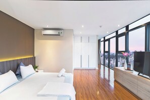 Una habitación de hotel moderna con una cama grande, televisión y vista a la ciudad.