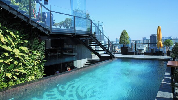 A rooftop pool with glass railings, a staircase, and a city view.