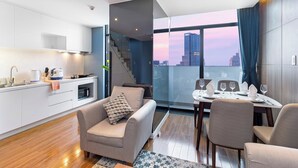 A modern apartment with a kitchen, dining area, and a view of the city skyline.
