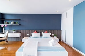 A modern hotel room with a large bed, a desk, and a bookshelf.