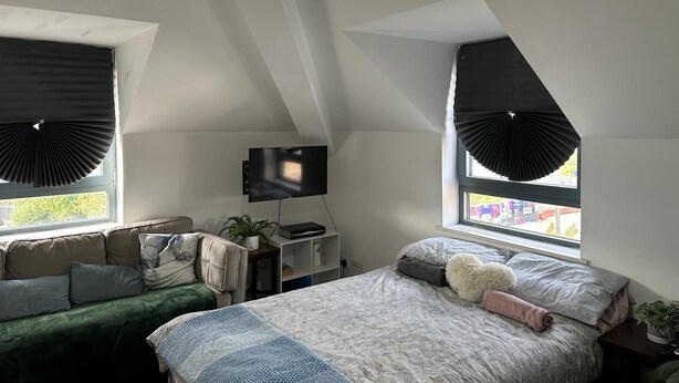 Ein Schlafzimmer mit Bett, Fernseher, Schreibtisch und Fenster mit Aussicht.