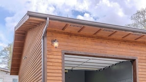 Ein Gebäude mit überdachter Garageneinfahrt, einer Betonauffahrt und einem Metalldach.