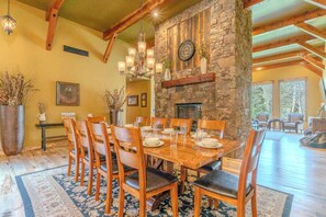 A dining area with a stone fireplace, wooden dining table, and chairs. - Snow Creek Lodge (West Yellowstone)