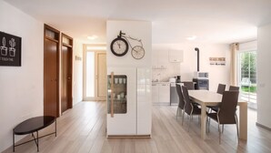 A modern kitchen with a dining area, wooden flooring, and a clock on the wall.